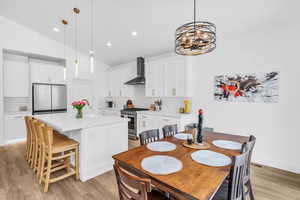 Dining area with vaulted ceiling, light wood-style floors, and recessed lighting