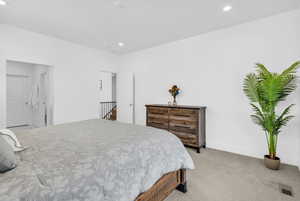 Bedroom featuring light carpet, recessed lighting, and ensuite bath