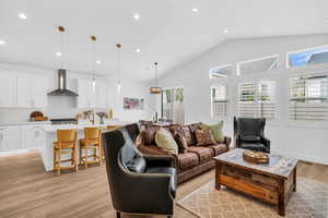 Living room with light wood finished floors, recessed lighting, and vaulted ceiling