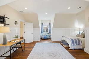Bedroom with wainscoting, a decorative wall, dark wood finished floors, and recessed lighting