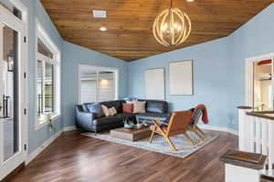 Living room featuring a vaulted wood ceiling, dark wood-type flooring, and hanging lights