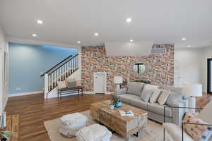 Living area featuring wood finished floors, an accent wall, recessed lighting, and wallpapered walls