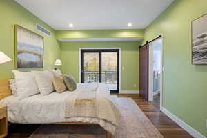 Bedroom featuring a barn door, access to outside, dark wood-type flooring, and recessed lighting