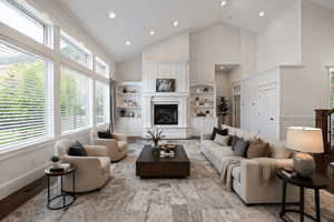 Living room with a glass covered fireplace, vaulted ceiling, recessed lighting, and wood finished floors