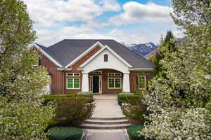 View of front of home featuring brick siding and roof with shingles