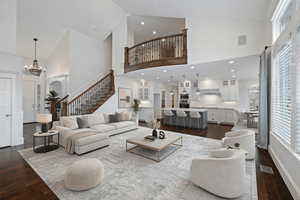 Living room with a chandelier, dark wood-type flooring, plenty of natural light, and vaulted ceiling