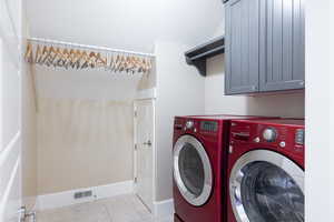 Laundry room with independent washer and dryer, light tile patterned floors, and cabinet space