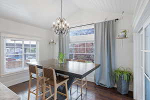 Dining space featuring dark wood finished floors, hanging lights, and a vaulted wooden ceiling