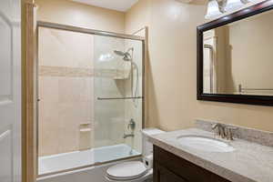 Bathroom with vanity and bath / shower combo with glass door