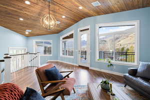 Living room featuring a vaulted wood ceiling, wood finished floors, hanging lights, and a mountain view