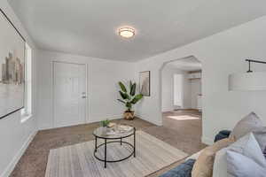 Living room featuring arched walkways and light wood-style floors