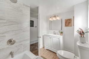 Full bathroom with vanity, light wood-style flooring, electric panel, and a tub