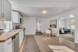 Kitchen featuring light wood finished floors, stainless steel appliances, butcher block counters, and white cabinets