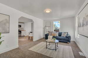 Living area with arched walkways and light colored carpet
