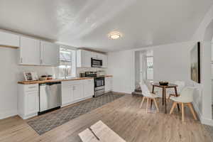 Kitchen featuring stainless steel appliances, light wood-type flooring, and white cabinetry