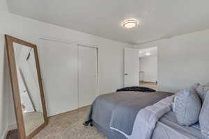 Bedroom with light colored carpet and a closet