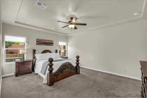 Carpeted bedroom featuring a raised ceiling, a ceiling fan, and a textured ceiling