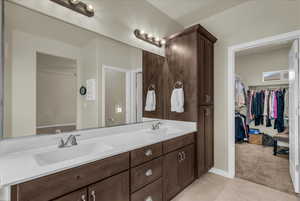 Full bathroom featuring a walk in closet, double vanity, light tile patterned floors, and light colored carpet