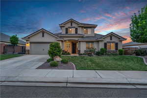 Traditional-style home with stone siding, stucco siding, an attached garage, and driveway