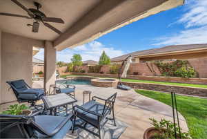 Fenced backyard featuring ceiling fan, a patio area, and a pool with connected hot tub