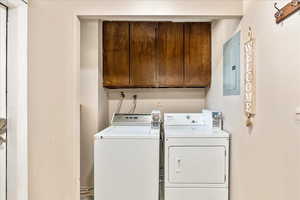 Laundry room with electric panel, cabinet space, and independent washer and dryer