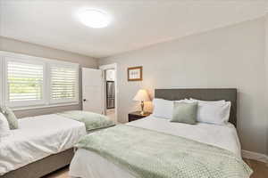 Bedroom with freestanding refrigerator and light wood-style floors
