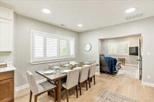 Dining room with light wood finished floors and recessed lighting