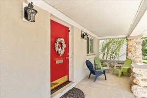 Entrance to property featuring covered porch and stucco siding