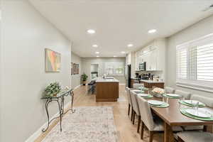 Kitchen with an island with sink, light wood-style floors, white cabinets, recessed lighting, and stainless steel appliances