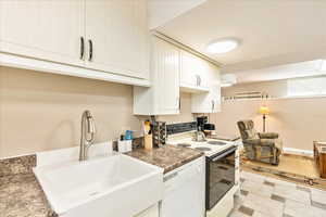 Kitchen featuring white appliances, white cabinets, dark countertops, and light flooring