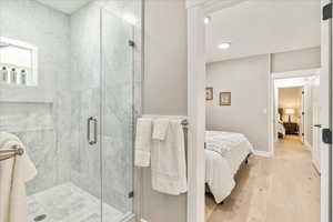 Full bathroom with ensuite bath, a marble finish shower, light wood finished floors, and recessed lighting