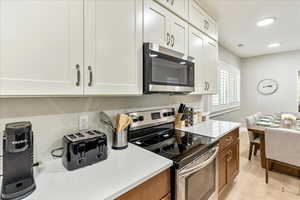 Kitchen featuring stainless steel appliances, light stone counters, light wood-style flooring, white cabinets, and recessed lighting
