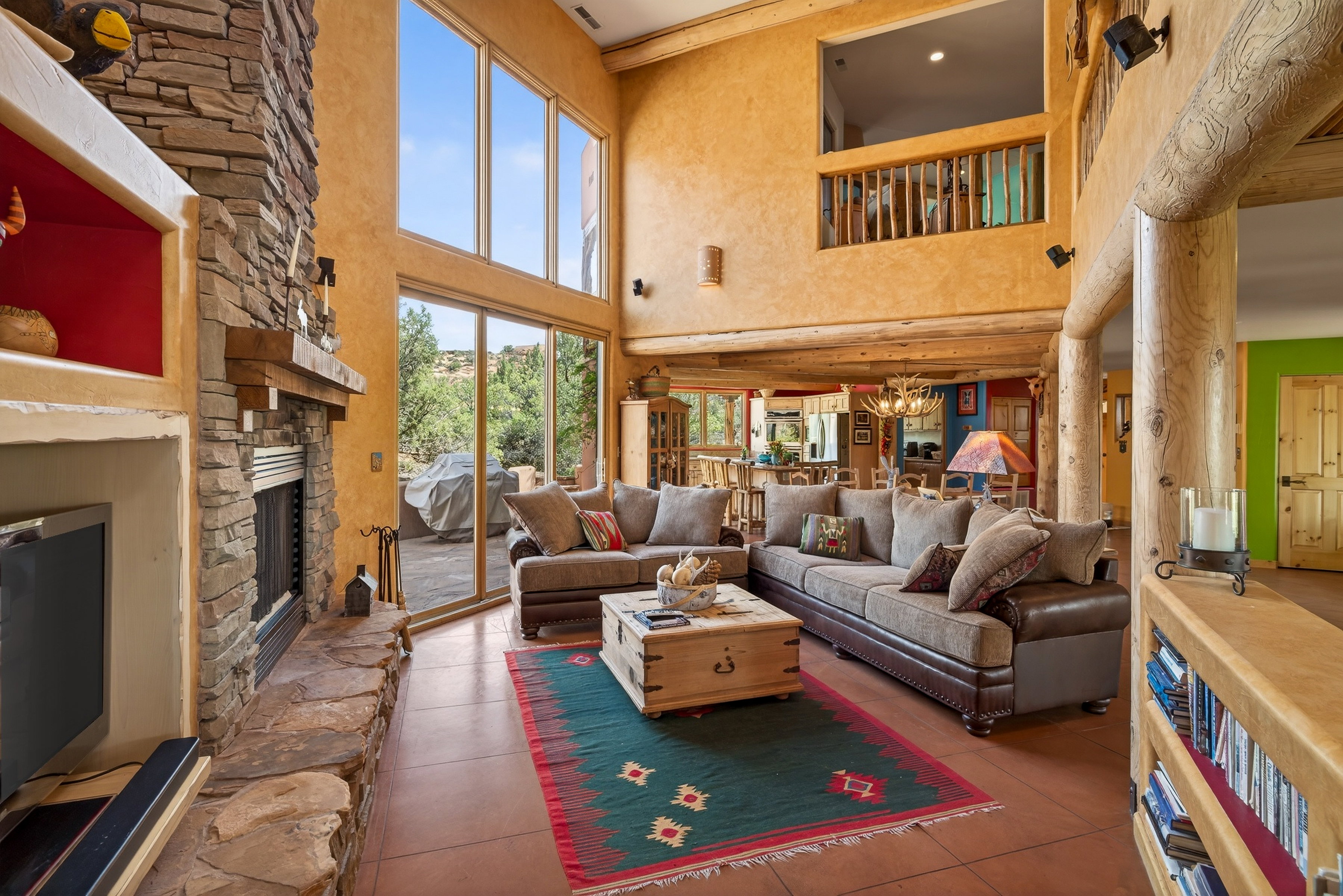 Living room with a high ceiling, a stone fireplace, and hanging lights