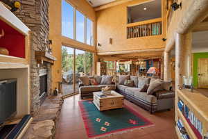 Living room with a high ceiling, a stone fireplace, and hanging lights