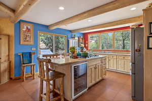 Kitchen with a kitchen breakfast bar, wine cooler, light wood finish cabinets, freestanding refrigerator, and recessed lighting