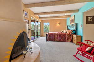 Bedroom featuring beam ceiling, light colored carpet, and access to outside