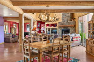Tiled dining room featuring healthy amount of natural light, hanging lights, a fireplace, and beam ceiling