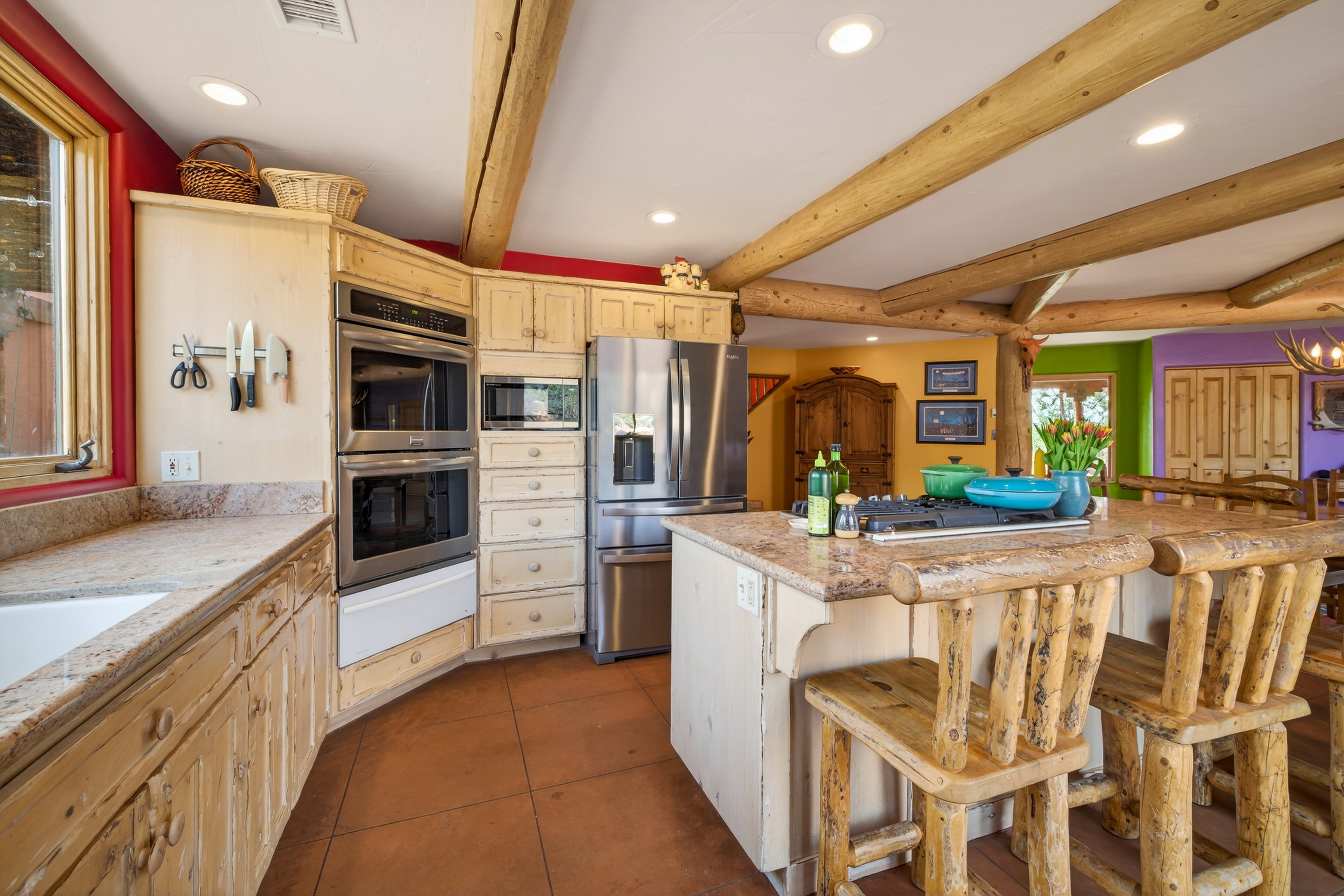Kitchen featuring recessed lighting, stainless steel appliances, a kitchen bar, beam ceiling, and dark tile patterned flooring