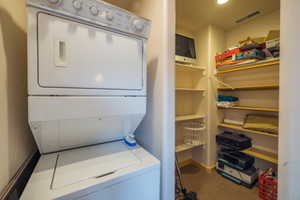 Laundry area with stacked washer and clothes dryer and baseboards