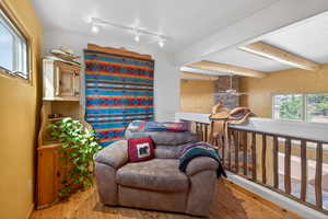 Living area with healthy amount of natural light, wood finished floors, rail lighting, and beam ceiling