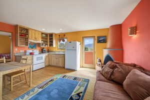 Kitchen with white appliances, open floor plan, light wood-style flooring, light countertops, and recessed lighting