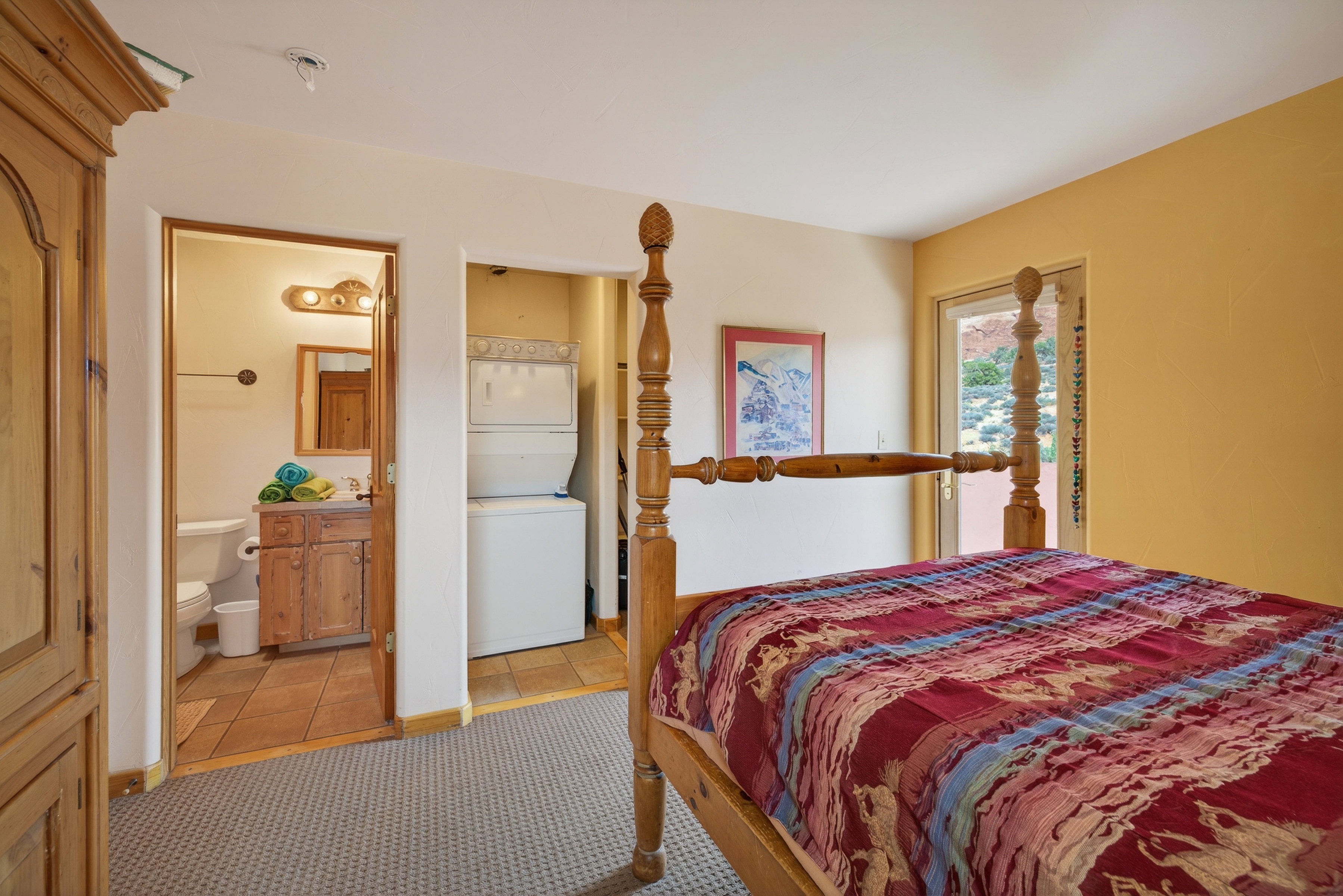 Bedroom with stacked washer and dryer, connected bathroom, and light tile patterned floors