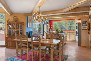 Dining room with healthy amount of natural light, suspended lighting, beamed ceiling, and light tile patterned floors