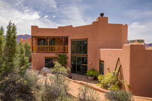 Rear view of property featuring a balcony, stucco siding, and a patio area