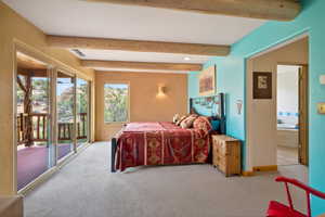 Bedroom with beamed ceiling, access to outside, and light carpet