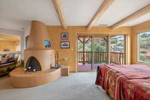 Bedroom featuring access to outside, a large fireplace, carpet floors, beam ceiling, and multiple windows