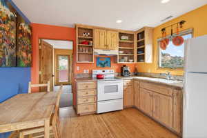 Kitchen featuring white appliances, light countertops, light wood-style flooring, open shelves, and light wood finish cabinetry