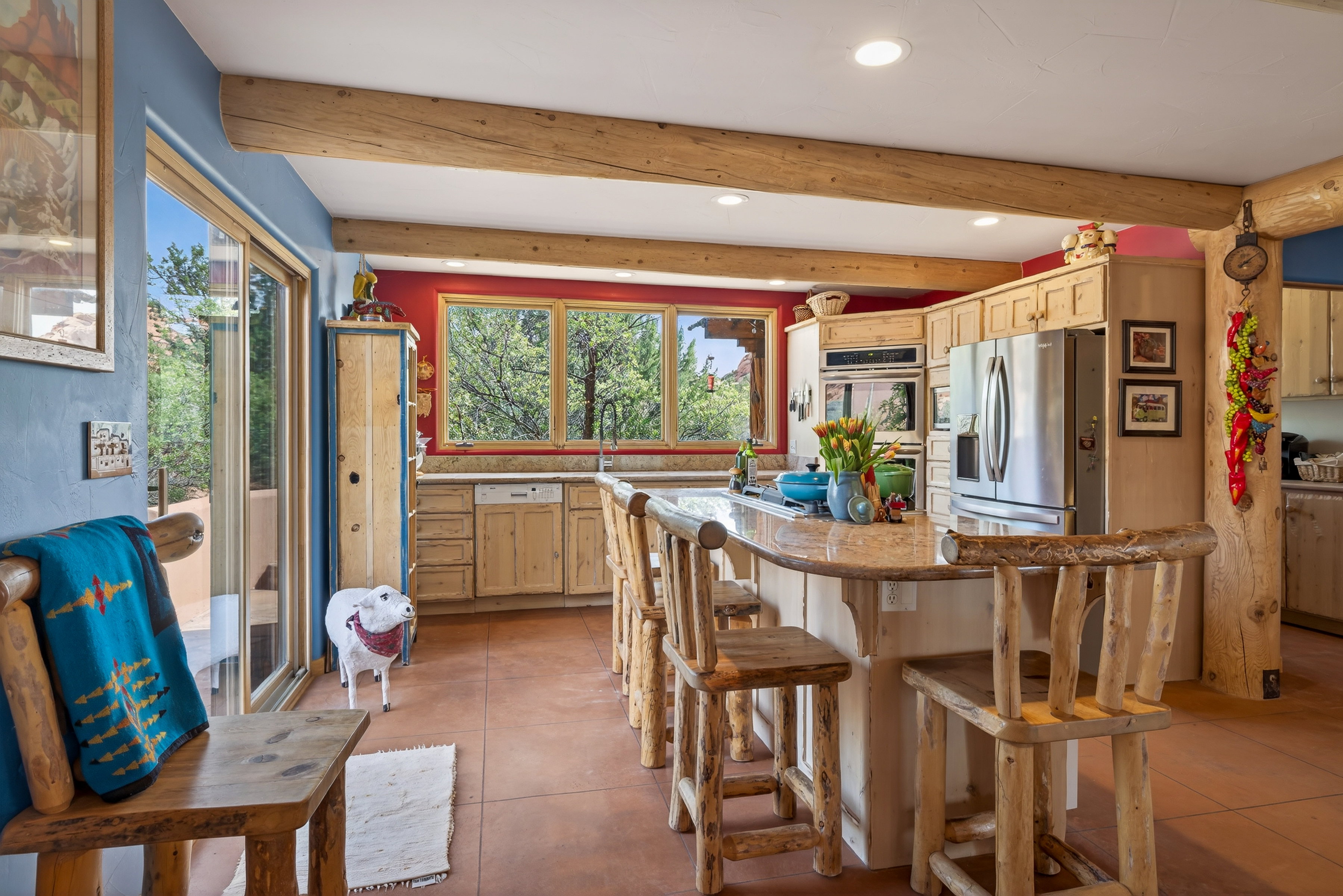 Kitchen with recessed lighting, stainless steel appliances, light wood finish cabinetry, light stone countertops, and a kitchen bar