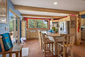 Kitchen with recessed lighting, stainless steel appliances, light wood finish cabinetry, light stone countertops, and a kitchen bar