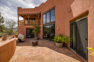 Rear view of property featuring a patio, stucco siding, and a balcony